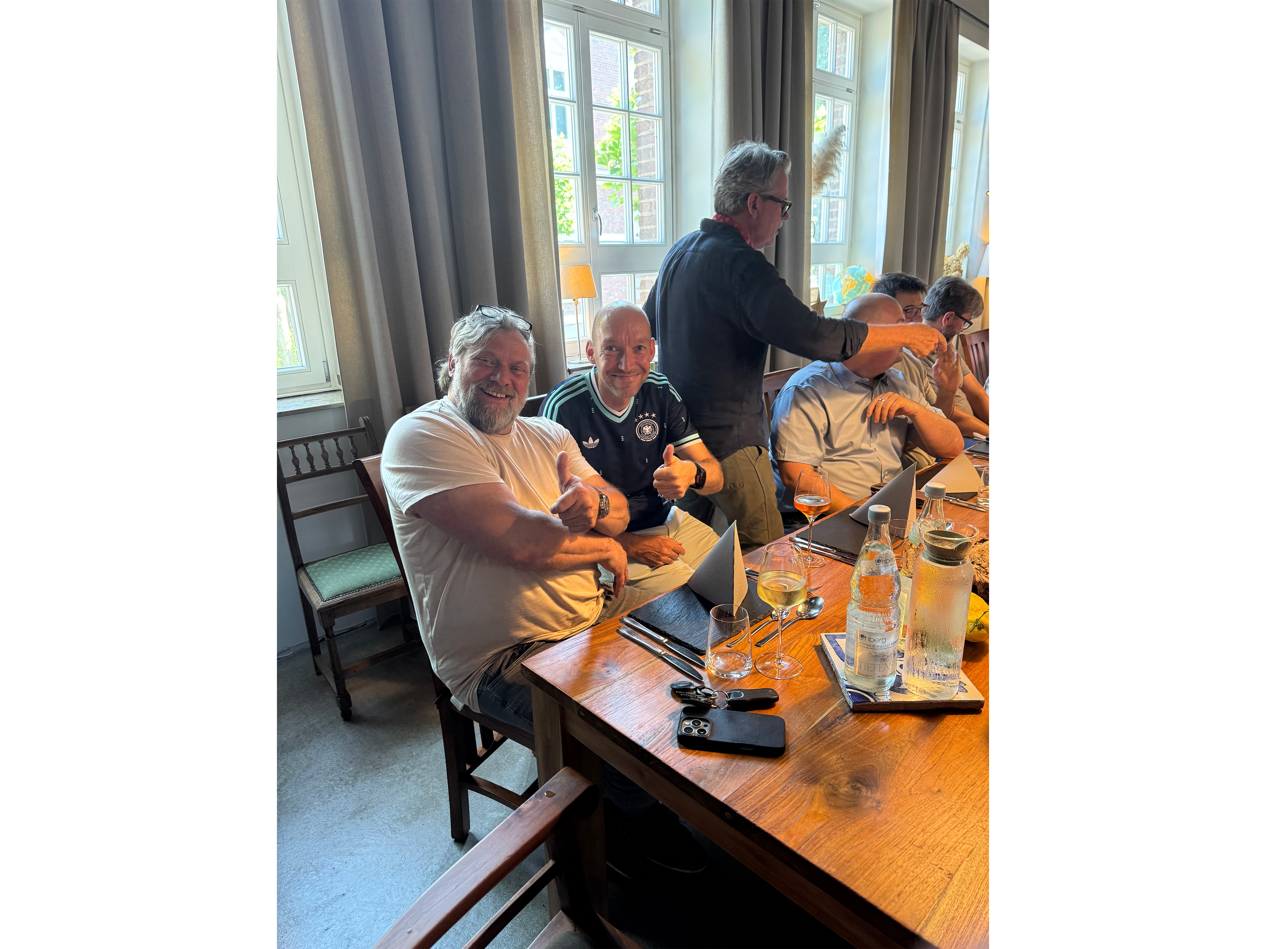 Gedeckter Tisch, Gläser, Flasche Wasser, Menschengruppe, Sitzmöbel