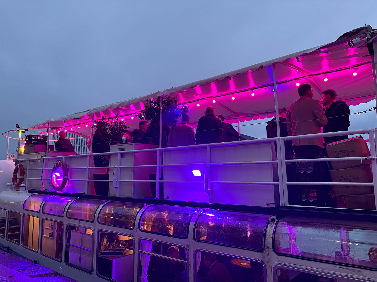 party boat, Lichterdach, pinkes Licht, Menschen an Deck, Gläsernes Boot